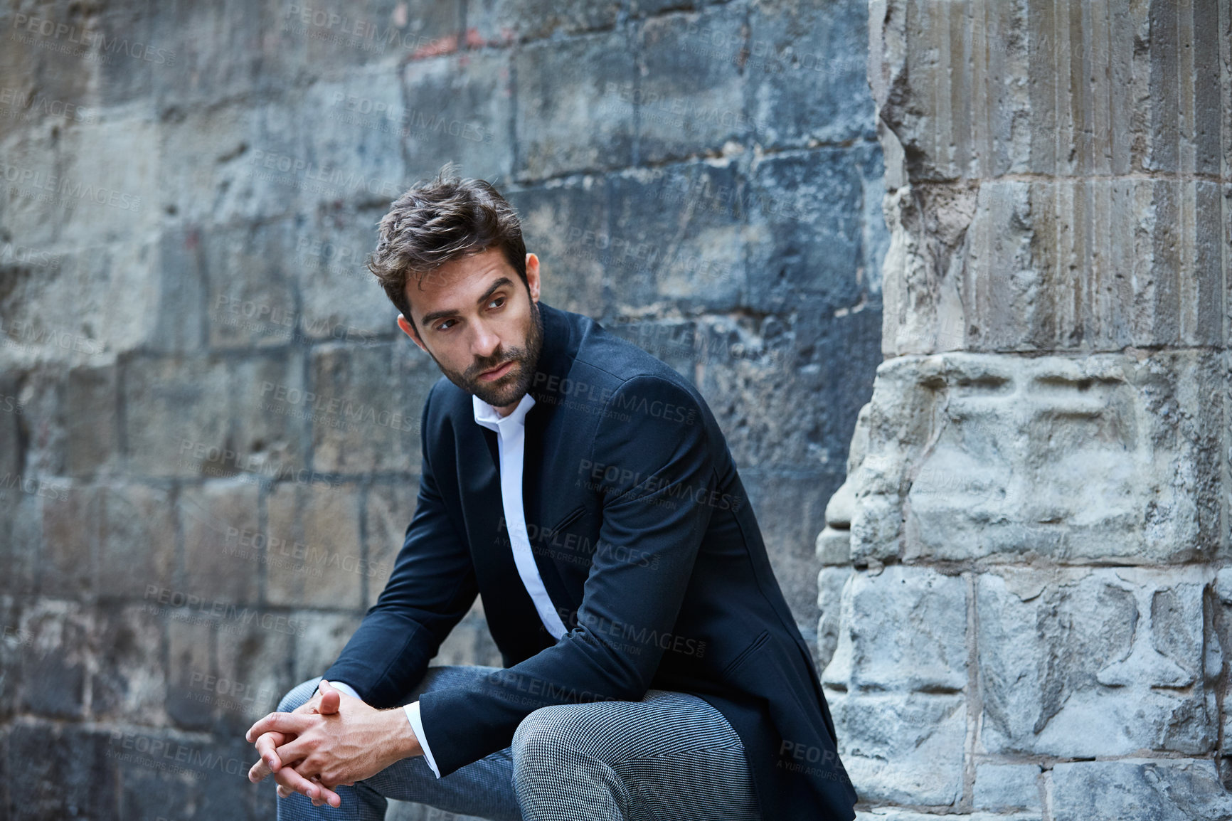 Buy stock photo Cropped shot of a handsome young businessman sitting in an urban alleyway