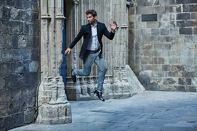 Buy stock photo Full length shot of a handsome young businessman leaping through an urban alleyway