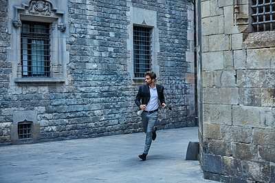 Buy stock photo Full length shot of a handsome young businessman running through an urban alleyway