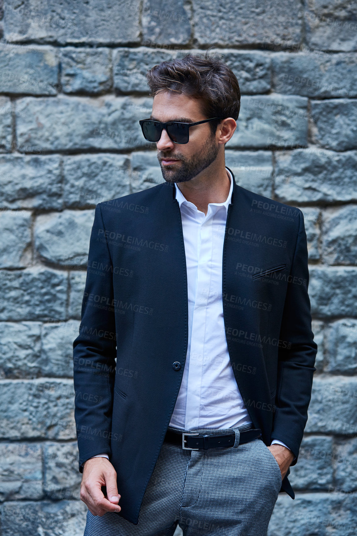 Buy stock photo Cropped shot of a handsome young businessman standing against a brick wall in an urban alleyway