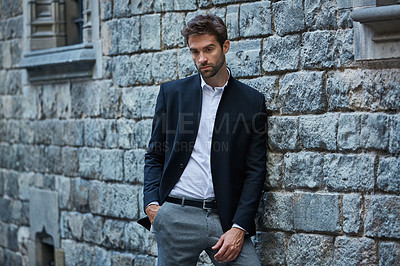 Buy stock photo Cropped shot of a handsome young businessman standing against a brick wall in an urban alleyway