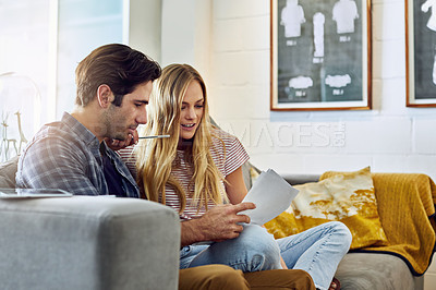 Buy stock photo Cropped shot of a young attractive couple planning their home budget together on the sofa in the living room at home