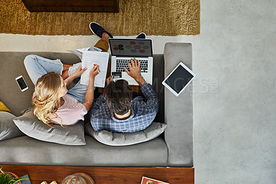 Buy stock photo High angle shot of a focused young unrecognizable couple working together on a laptop while being seated on a couch at home