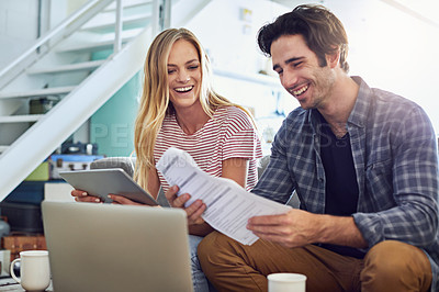 Buy stock photo Shot of a cheerful young couple working together on a digital tablet while being seated on a couch at home