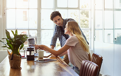 Buy stock photo Shot of a focused young couple doing paperwork together while being seated next to a table at home