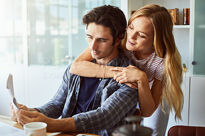 Buy stock photo Shot of a focused young couple doing paperwork together while being seated next to a table at home