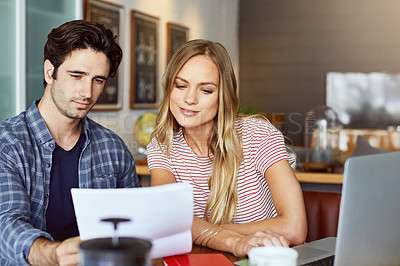 Buy stock photo Shot of a focused young couple doing paperwork together while being seated next to a table at home