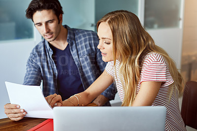 Buy stock photo Shot of a focused young couple doing paperwork together while being seated next to a table at home