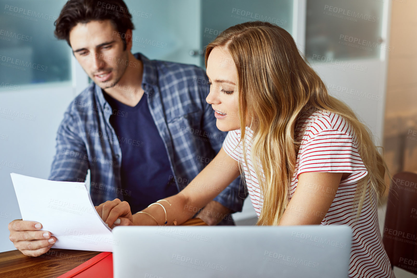 Buy stock photo Shot of a focused young couple doing paperwork together while being seated next to a table at home