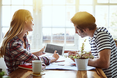 Buy stock photo Shot of a focused young couple drawing plans and choosing colors for the renovation of their house while making use of a digital tablet