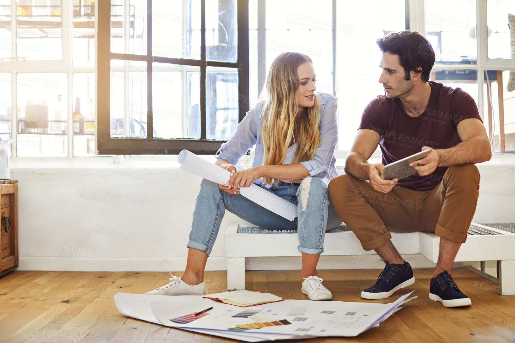 Buy stock photo Shot of a focused young couple drawing plans and choosing colors for the renovation of their house