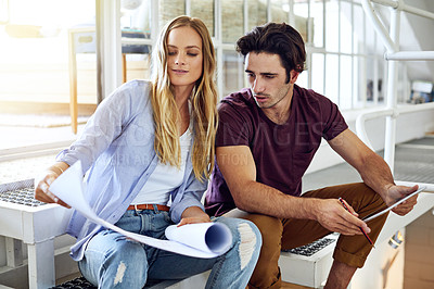 Buy stock photo Shot of a focused young couple drawing plans and choosing colors for the renovation of their house