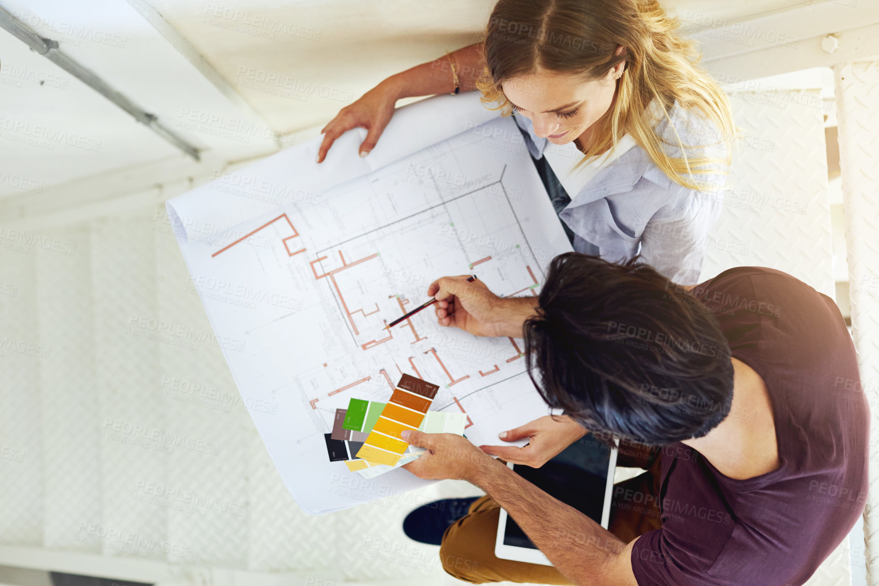 Buy stock photo High angle shot of a focused young couple drawing plans and choosing colors for the renovation of their house