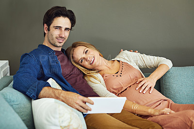 Buy stock photo Shot of a young man and his pregnant wife using a digital tablet together on the sofa
