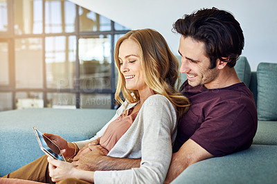 Buy stock photo Shot of a young man and his pregnant wife using a digital tablet together on the sofa