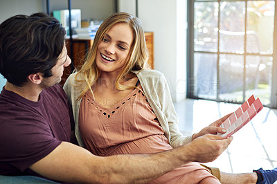 Buy stock photo Shot of a young man choosing color swatches with his pregnant wife to decide the color of the room