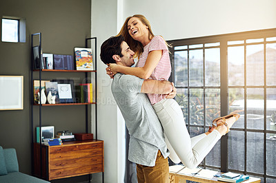 Buy stock photo Shot of a happy young man lovingly picking up his wife at home