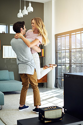 Buy stock photo Shot of a happy young man lovingly picking up his wife at home