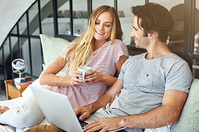 Buy stock photo Shot of a young couple using a laptop together while relaxing on the bed at home