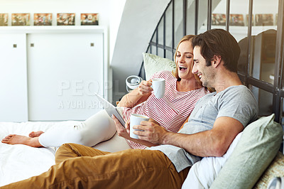 Buy stock photo Shot of a young couple using a digital tablet together while relaxing on the sofa at home