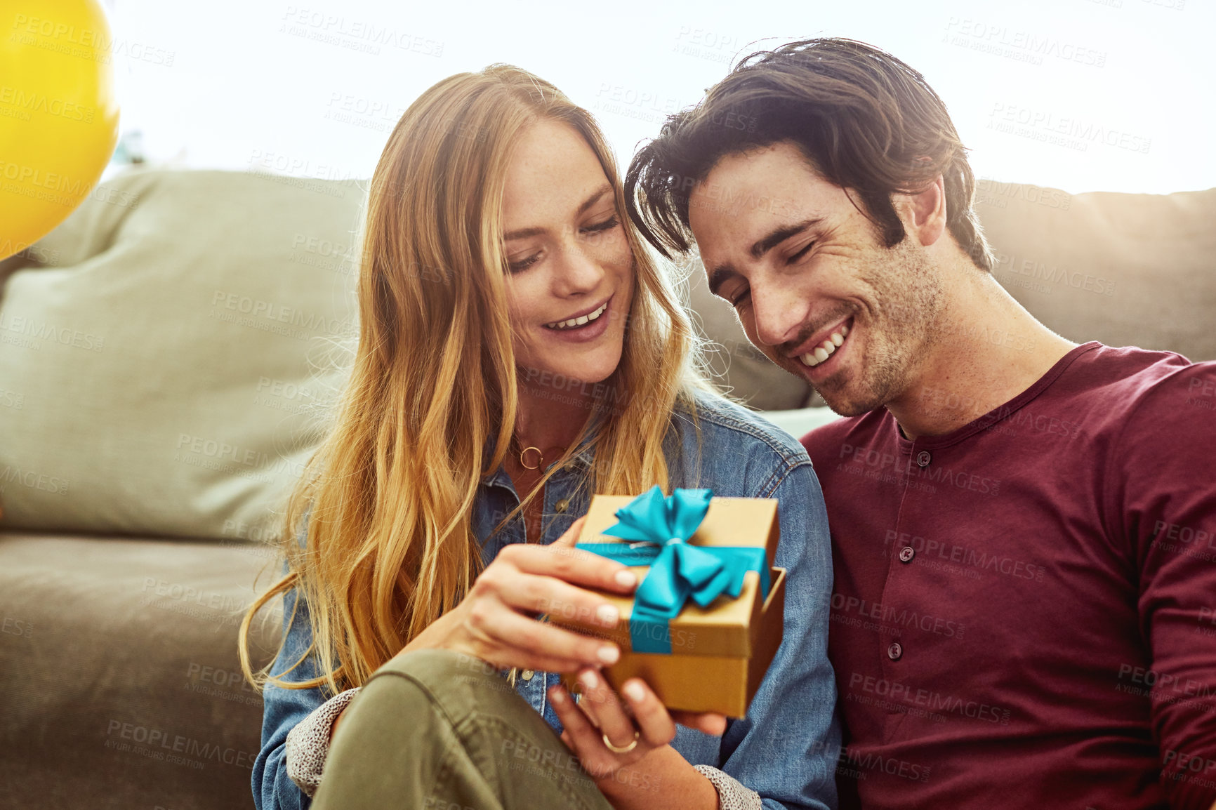 Buy stock photo Shot of a young woman giving her husband a gift at home