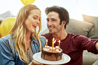 Buy stock photo Shot of a young couple having cake while celebrating a birthday at home