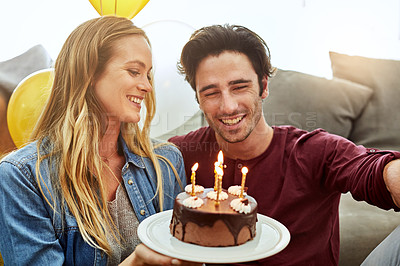 Buy stock photo Shot of a young couple having cake while celebrating a birthday at home