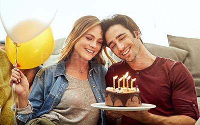Buy stock photo Shot of a young couple having cake while celebrating a birthday at home