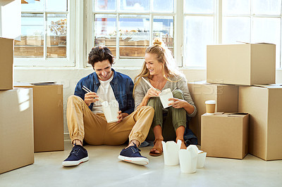 Buy stock photo Shot of a young couple eating takeout while taking a break moving into their new home