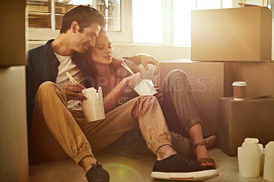 Buy stock photo Shot of a young couple eating takeout while taking a break moving into their new home