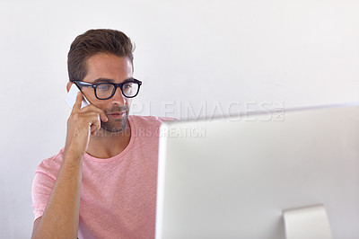 Buy stock photo Shot of a young businessman talking on his phone while sitting at his desk