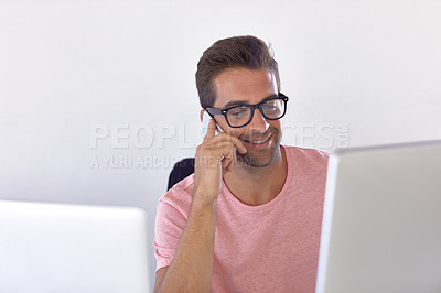 Buy stock photo Shot of a young businessman talking on his phone while sitting at his desk