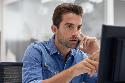Buy stock photo Shot of a young businessman talking on his phone while sitting at his desk