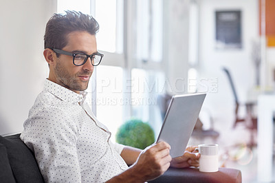 Buy stock photo Cropped shot of a young businessman using his digital tablet in his office