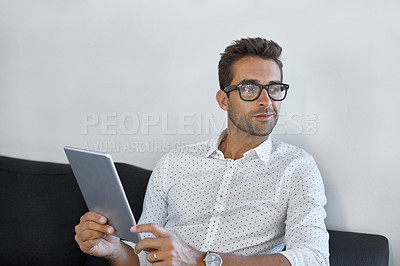 Buy stock photo Cropped shot of a young businessman using his digital tablet in his office