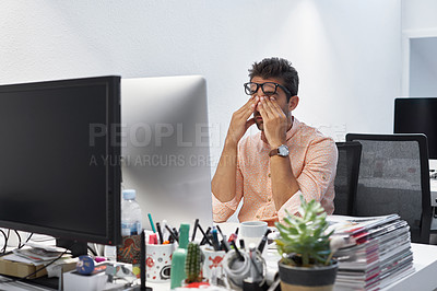 Buy stock photo Shot of a businessman looking exhausted while sitting at his desk