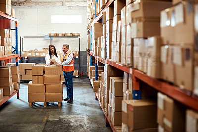 Buy stock photo Shot of a mature man and woman using a digital tablet while working together in a warehouse