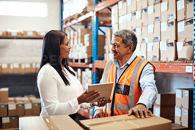 Buy stock photo Shot of a mature man and woman using a digital tablet while working together in a warehouse