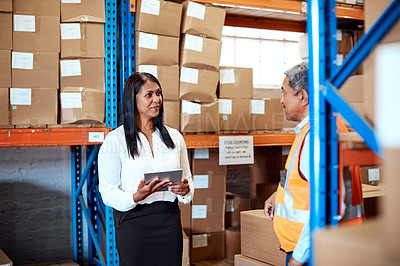 Buy stock photo Shot of a mature man and woman using a digital tablet while working together in a warehouse
