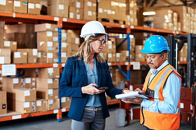 Buy stock photo Shot of a man and woman having a discussion while working together in a warehouse