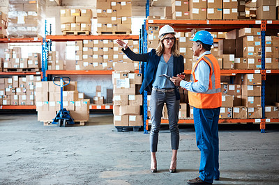 Buy stock photo Shot of a man and woman having a discussion while working together in a warehouse