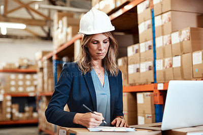 Buy stock photo Shot of a young woman using a laptop while working in a warehouse