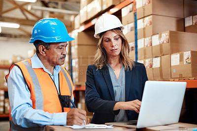 Buy stock photo Shot of a man and woman using a laptop while working together in a warehouse