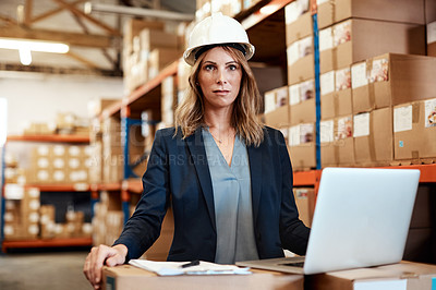 Buy stock photo Shot of a young woman using a laptop while working in a warehouse