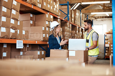 Buy stock photo Shot of a young man and woman using a laptop while working together in a warehouse