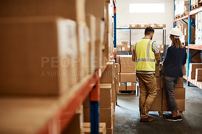 Buy stock photo Shot of a young man and woman having a discussion while working together in a warehouse