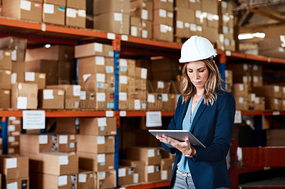 Buy stock photo Shot of a young woman using a digital tablet while working in a warehouse