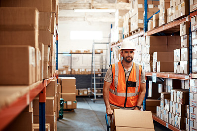 Buy stock photo Shot of a young man moving boxes on a trolley in a warehouse
