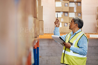 Buy stock photo Shot of a mature man using a clipboard while working in a warehouse