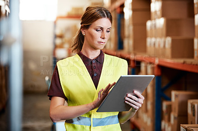 Buy stock photo Shot of a young woman using a digital tablet in a warehouse